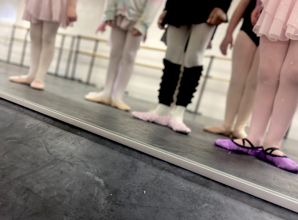 ballet dancers showing off their shoes in the mirror