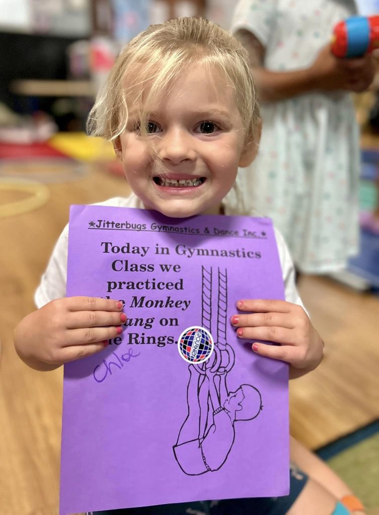 a girl holding a purple paper about gymnastics class