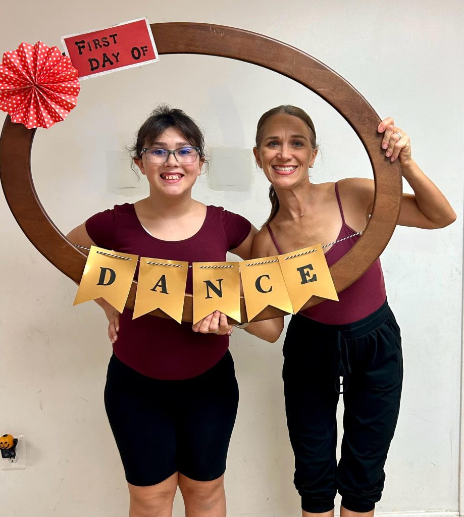 dance teacher posting with tap studio with a dance sign