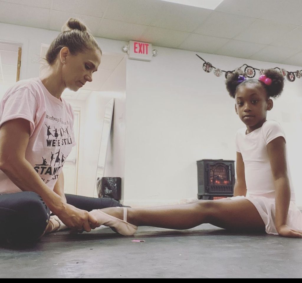 dancer teacher helping dancer stretch feet